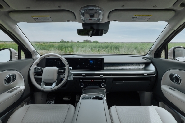 The IONIQ 9 dashboard viewed from the second row, with a curved display spanning the driver's cluster and the center screen