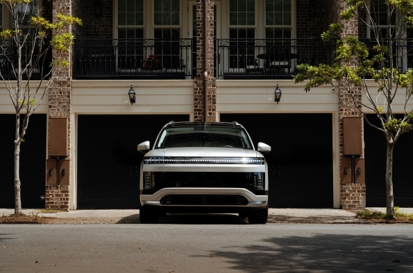 The front of a Hyundai IONIQ 9 parked on a residential street, showing the full-width light bar